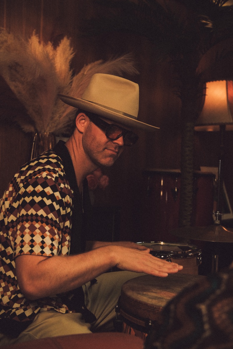 Percussionist in wide-brim hat, bongos in candlelit lounge